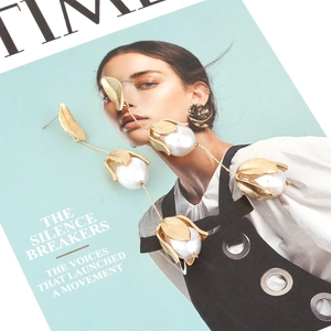 Close-up of elegant gold leaf and pearl tassel earrings on a fashion magazine background