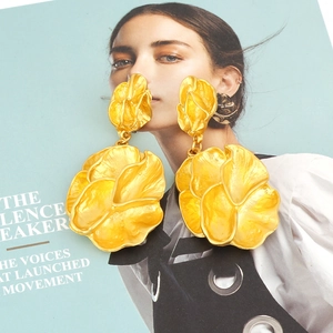 Macro detail of large matte gold floral earrings with overlapping metal petals