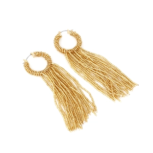 Détail des boucles d'oreilles à franges de perles dorées avec motif bohème tissé