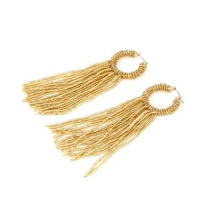 Détail de boucles d'oreilles dorées avec pampilles en perles tissées multicouches