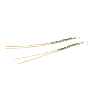 Vue détaillée des longues boucles d'oreilles pompon dorées avec perles vertes et crochets