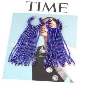 Vue détaillée de boucles d'oreilles bohèmes en perles avec pompons sur un magazine
