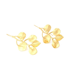 Detailed macro view of matte gold leaf earrings with intricate vein textures and hooks