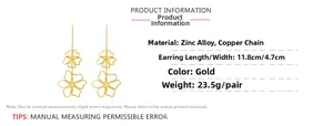 Detail view of large gold cutout floral drop earrings with length and width dimensions