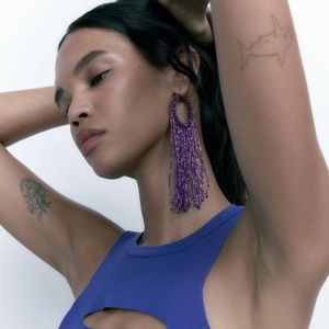 Boucles d'oreilles bohèmes à pompons de perles mauves sur le profil d'un mannequin