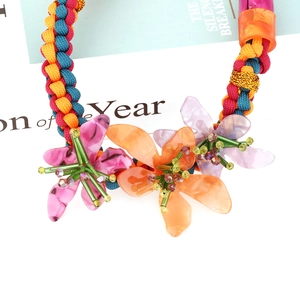 Détail d'un collier tressé coloré à la main avec des pendentifs fleurs en acrylique