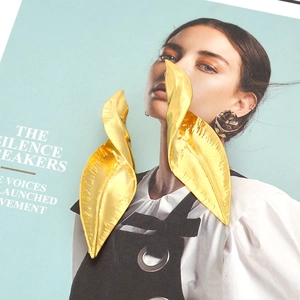 Macro shot of gold-plated leaf earrings with detailed veins on a fashion magazine