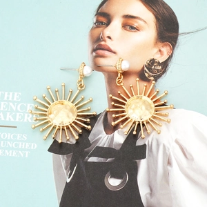 Golden sunflower earrings with faux pearl and hammered texture on artistic background