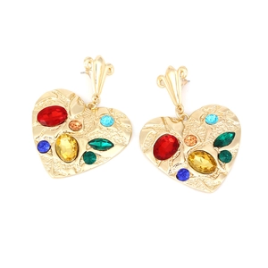 Detail of gold heart earrings with colorful rhinestones and hammered metal texture