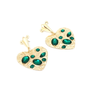 Detail of vintage heart earrings with gold hammer texture and emerald green crystals