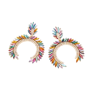 Macro detail of gold-plated geometric C-hoop earrings featuring colorful marquise rhinestones