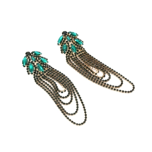 Detail view of long tassel earrings featuring green crystal clusters and black rhinestone chains