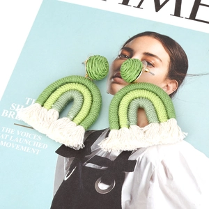 Detalle de pendientes boho de arcoíris hechos a mano con borlas de algodón verde