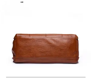 Detail view of the brown leather handbag base showing precise stitching and wide structure
