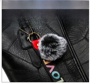 Détail d'un cabas en cuir noir avec pompon gris et bandoulière LOVE tissée