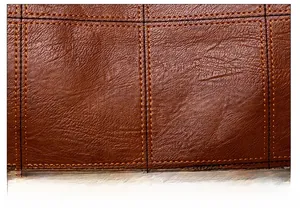 Close-up of brown pebbled leather texture with orange contrast stitching in a grid pattern