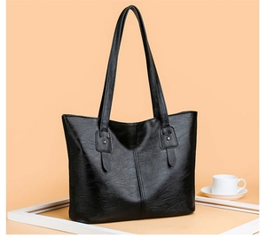 Détail d'un sac cabas en cuir noir avec coutures verticales et rivets sur les anses