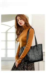 Détail d'un grand sac cabas noir avec texture géométrique porté à l'épaule par un mannequin