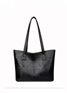 Détail du cabas noir montrant le design patchwork texturé et la qualité des coutures
