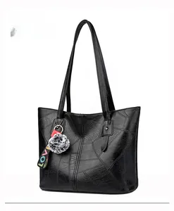 Détail du grand sac cabas noir à texture géométrique et breloque peluche LOVE