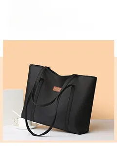 Detail of black nylon tote bag featuring a brown leather patch and sturdy handles