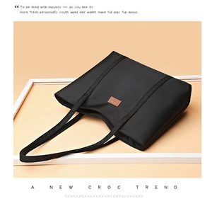 Close-up of black nylon tote bag with leather logo detail and shoulder strap for women