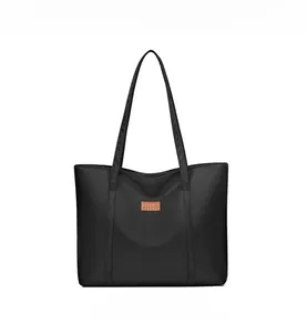Detail of minimalist black nylon tote bag featuring a leather patch and slim shoulder straps