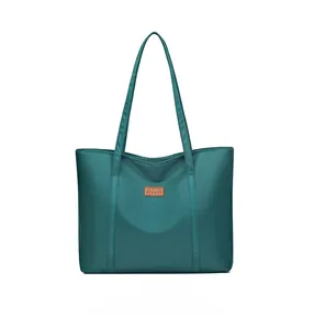 Detailed close-up of dark green waterproof nylon tote bag with leather logo patch