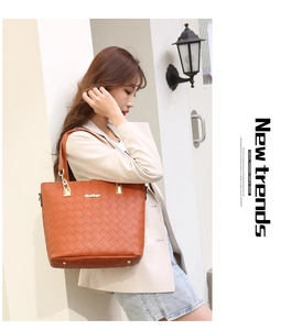 Close-up of brown woven texture tote bag with gold logo on a stylish woman outfit