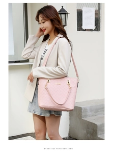 Pink woven tote bag featuring gold chain handles and adjustable strap on street background