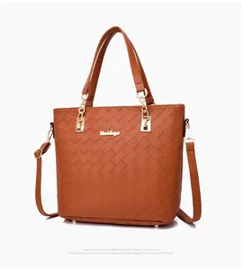 Detail of camel woven tote bag showing gold logo and premium metal studs on bottom