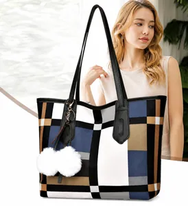 Detail of checkered tote bag featuring a leather strap and white pompom charm