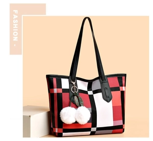 Detail of large tote bag with red plaid pattern and plush cherry charm hanging on it