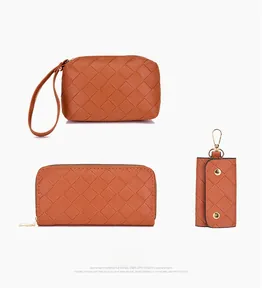 Detail of woven brown leather wallet set with golden zippers and wrist strap