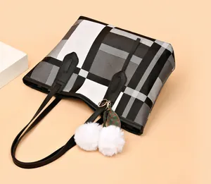 Detail of checkered tote bag with lychee texture and plush pompom charm accessory