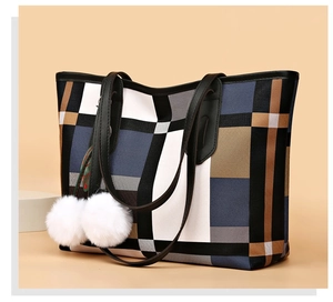 Close-up of geometric color block tote bag with black straps and white pom-pom charms