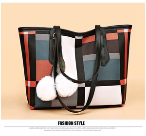 Close-up of geometric color block tote bag with white plush ball charm and fine leather texture