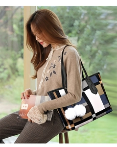 Detail of color-block geometric tote bag with black leather straps and pompom charm