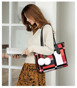 Detail of checkered tote bag with dual black leather handles and white pompom charm