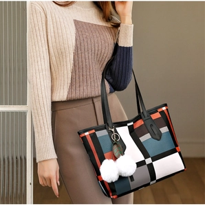 Detailed view of color-block tote bag with geometric pattern and white pompom charm