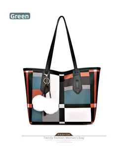 Detail of printed geometric tote bag with green accents, leather handles and pom-pom charm