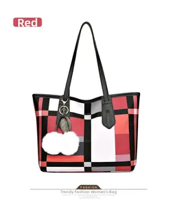 Detail of red checkered tote bag featuring a white faux fur pompom and black leather handles