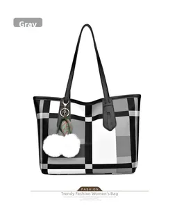 Close-up of grey plaid tote bag with black strap and white pompom leaf charm detail