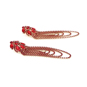 Detail view of long tassel earrings with red rhinestones and gold chain fringes