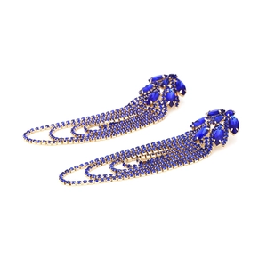 Macro detail of long royal blue rhinestone tassel earrings with golden geometric finish