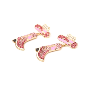 Detailed view of pink cowboy boot and hat earrings with crystal stones and gold plating