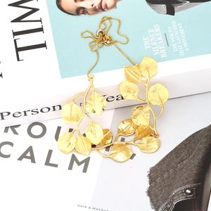 Adjustable golden leaf necklace with detailed veins on vintage style magazine