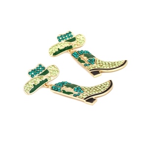 Detail of western cowboy boot earrings with green rhinestones and enamel on gold base