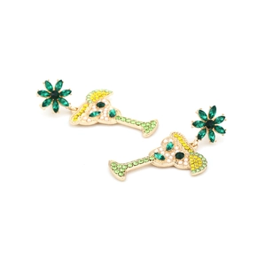 Macro shot of gold alloy cocktail glass earrings with green rhinestones and floral stud