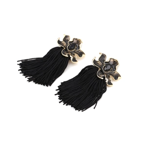Detail of long black tassel earrings with gold enamel orchid design and crystal accents